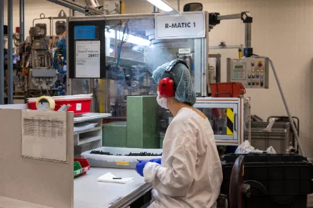 Operadora em linha de produção industrial — foto institucional da AKAE